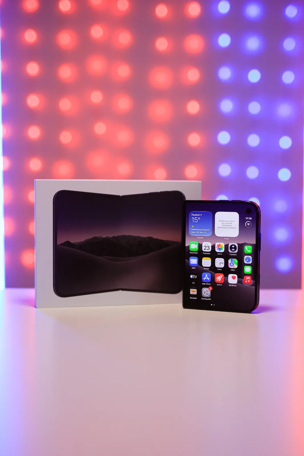 iPhone Duo lângă cutie, cu ecranul exterior pornit